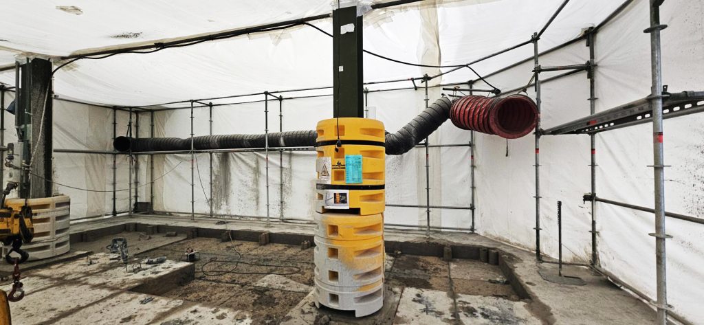 Conduites de ventilation traversant la zone confinée pour extraire la poussière et insuffler de l’air frais.